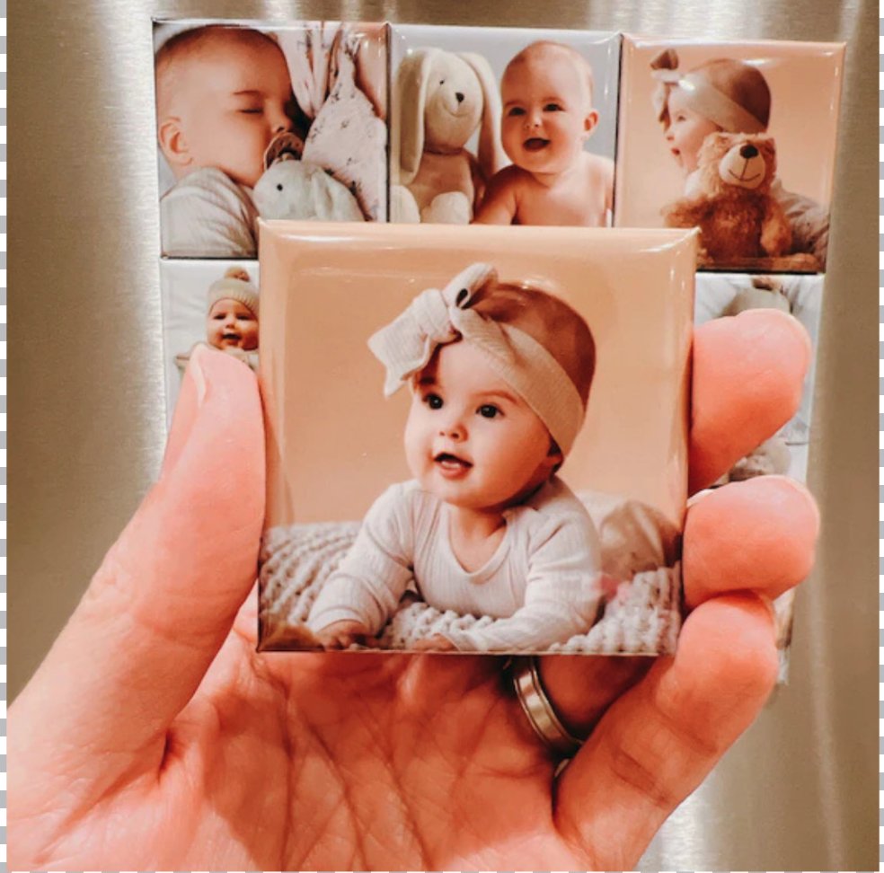 Hand met fotomagneet van een baby op de koelkast