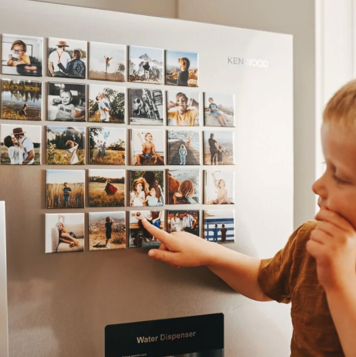 Jongen bij fotomagneten op de koelkast